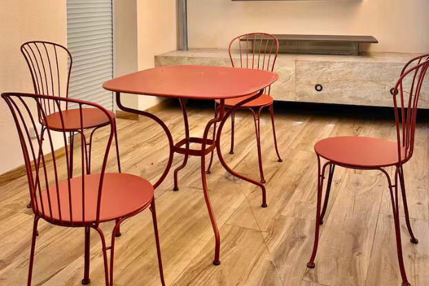 une table et quatre chaises rouges disposés sur une terrasse en bois